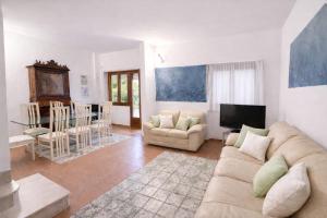 a living room with a couch and a television at Villa summertime walking distance from the sea with garden in Fregene