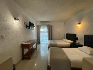 a hotel room with two beds and a desk at Hotel Dos Mundos, Isla Cozumel in Cozumel