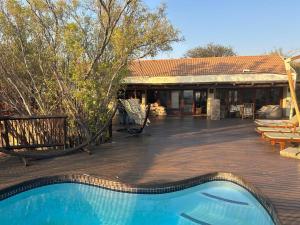 a house with a wooden deck and a swimming pool at Luxury Villa at Elements Golf Course - Bela Bela in Warmbaths