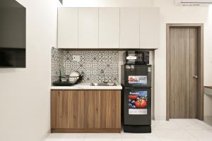 a kitchen with white cabinets and a black refrigerator at Soi by La Doma Express in Ho Chi Minh City