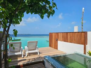 a deck with two chairs and a swimming pool at Lagoon View Maldives in Bodufolhudhoo