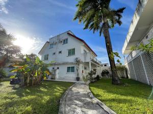 a white house with a palm tree next to a yard at Hotel Dos Mundos, Isla Cozumel in Cozumel