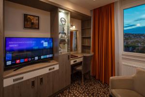 a hotel room with a tv and a desk and a window at Hotel Charles in Budapest +81 photos