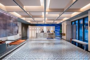 a lobby with a tile floor with two people in the background at Novotel Yangquan High-Tech Zone in Yangquan +84 photos