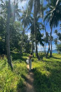 a woman walking down a dirt road with palm trees at Darocotan Shipwreck Camping in El Nido +12 photos