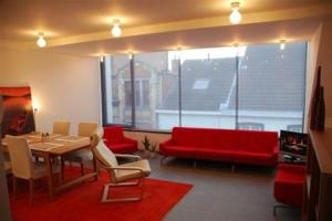un soggiorno con tavolo e divano rosso di Aparthotel Malpertuus a Aalst
