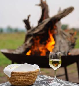 a glass of wine sitting on a table next to a fire at Daga Tented Camp in Mikumi