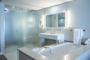 a bathroom with a tub and a sink and a shower at Blaauwberg Beach Hotel in Bloubergstrand +169 photos