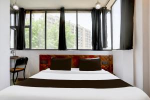 a bedroom with a large white bed with windows at Hotel O MP Nagar Near Rachna Tower in Bhopal