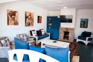 a living room with blue chairs and a fireplace at Hermanus Backpackers & Budget Accommodation in Hermanus