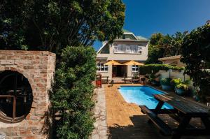 a house with a swimming pool with a bench and a house at Hermanus Backpackers & Budget Accommodation in Hermanus