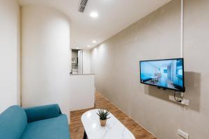 a living room with a blue couch and a tv on a wall at Meworld Hotel - Daan in Taipei