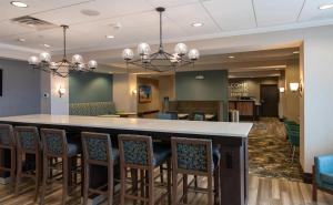 a lobby with a bar with chairs around it at Hampton Inn Orange City in Orange City