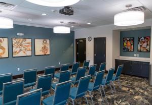a conference room with blue chairs and paintings on the walls at Hampton Inn Orange City in Orange City +23 photos