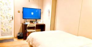 a bedroom with a bed and a desk with a television at Baiyuan Hotel Changgang Baogang Avenue Metro Station Branch in Guangzhou