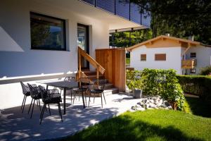 a patio with chairs and a table and a house at Apartment Waldfrieden in Pfons