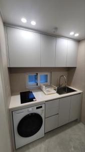 a kitchen with white cabinets and a sink and a dishwasher at 모던한 스테이 in Samgong