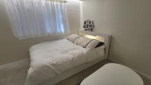 a small bedroom with a white bed with a window at 모던한 스테이 in Samgong