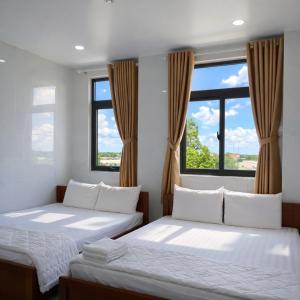 two beds in a room with windows at Bảo Di Sóc Trăng Hotel in Soc Trang