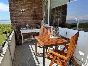 a wooden table and chairs on a patio with a window at Langeneß Whg 15 Strandtraum in Wyk auf Föhr
