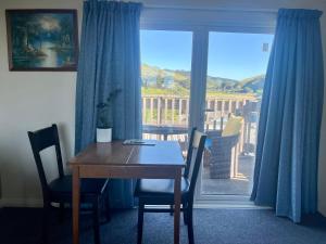 a dining room table and chairs with a view of a balcony at Makara Beach Escape in Wellington