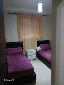 a bedroom with two beds with purple sheets and a window at jardaine d'Ifrane in Ifrane +2 photos