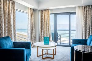 a living room with blue chairs and a table at Blaauwberg Beach Hotel in Bloubergstrand