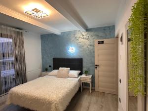 a bedroom with a white bed and a plant at Stelele Oltului in Călimăneşti