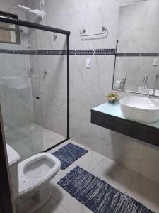 a bathroom with a shower and a toilet and a sink at Suíte Tranquila em Ambiente Familiar em Antares in Maceió +6 photos