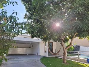 a white garage with a tree in front of it at Suíte Tranquila em Ambiente Familiar em Antares in Maceió