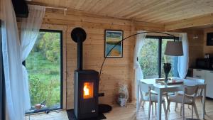 a room with a wood stove in a room with a table at Les Ecolodges du Lac in Chambon-sur-Lac