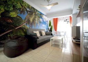 a living room with a couch and a palm tree mural at Alma Brizo Suites in Grao de Castellón