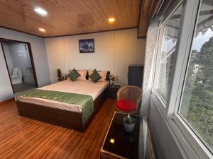 a bedroom with a bed and a large window at Tholangi Homes in Darjeeling