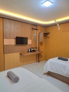 a bedroom with a bed and a tv on a wall at 7 Day Inn in Gili Trawangan