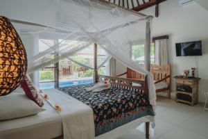 a bedroom with a bed with a canopy at Frangipani Beach Hotel in Lovina