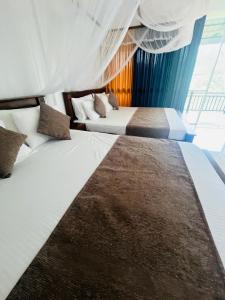 two beds in a hotel room with curtains at Blissbarn Inn Ella in Ella +33 photos