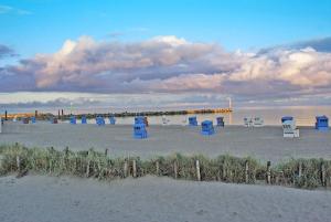 a group of blue chairs sitting on the beach at Blockhaus mit grosser überdachter Terrasse in Damp