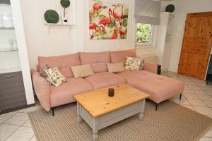 a living room with a pink couch and a coffee table at Blockhaus mit grosser überdachter Terrasse in Damp