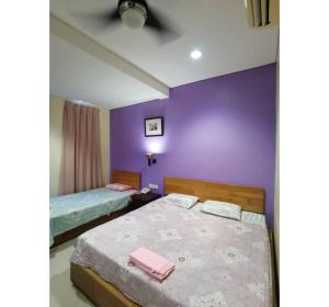 a bedroom with two beds and a purple wall at Hotel O Pavilion Inn Hotel in Lumut