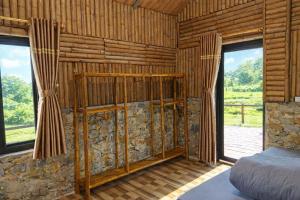 a bedroom with a bed in a wooden room with windows at Y Sao Homestay in Hòa Bình