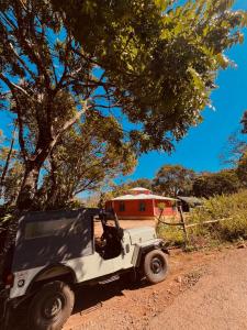 a white jeep parked on a dirt road next to a tree at Westernmagic in Idukki