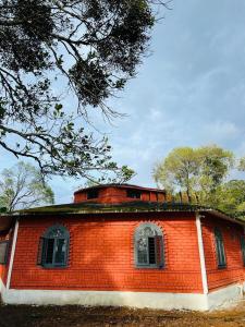 a red brick building with windows and trees in the background at Westernmagic in Idukki
