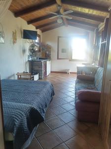 a bedroom with a bed and a couch and a ceiling fan at ECO Affittacamere Casa Maica Eco guesthouse in Stintino