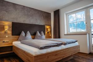 a bedroom with a bed with a wooden headboard and a window at B&B Gästehaus Alpenblick in Lermoos
