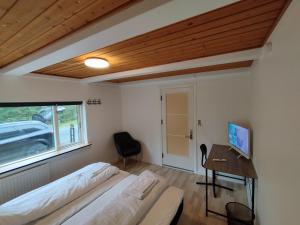 ein Schlafzimmer mit einem Bett und einem Schreibtisch mit Computer in der Unterkunft Fjeldgaard - Aarup in Årup