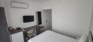 ein weißes Zimmer mit einem Bett und einem Fernseher in der Unterkunft Aykaç Hotel in Silifke