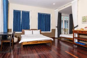 a room with a bed and a table and blue curtains at Olive Villa in Khu Chi Lăng