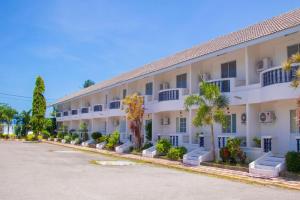 a large white building with palm trees in a parking lot at Bangsaphan Resort in Bang Saphan
