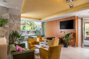 a lobby with chairs and tables and a tv at Hotel Aria in Rimini