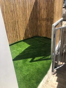 Eine Terrasse mit grünem Rasen neben einem Holzzaun in der Unterkunft Simple Room in Mas'ada